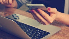 Person on laptop using smartphone