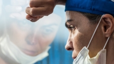 A medical worker leans at a window