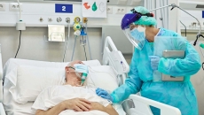 Person wearing PPE at hospital bed