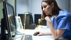 Person in scrubs at computer. Photo: Diego Cervo/Getty Images