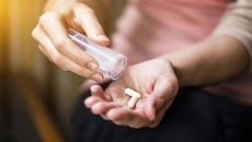 Person dispensing two pills into hand