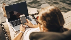 Physician on beach working on laptop and phone