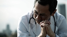 Medical professional seated, appearing dejected