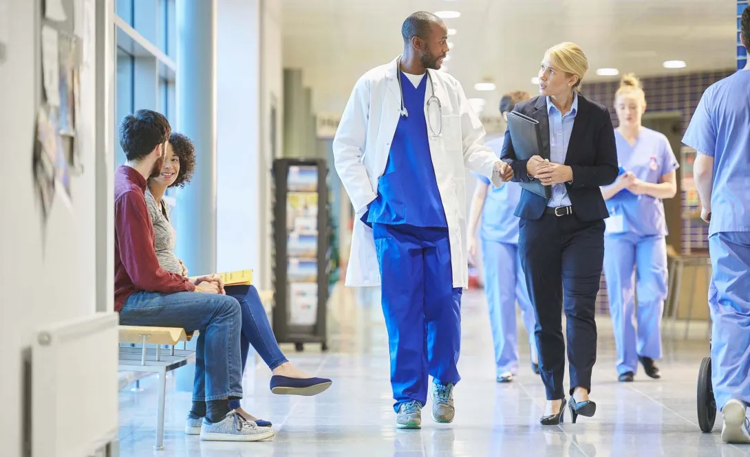 Physicians and others walking in hospital corridor Physicians and others walking in hospital corridor