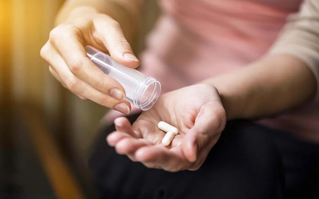 One hand dispenses pills into another One hand dispenses pills into another