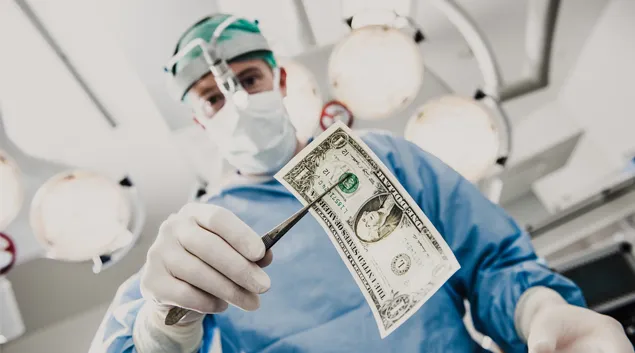 Person in PPE holding dollar bill with forceps Person in PPE holding dollar bill with forceps