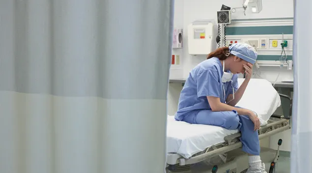 Exhausted medical worker sits on hospital bed