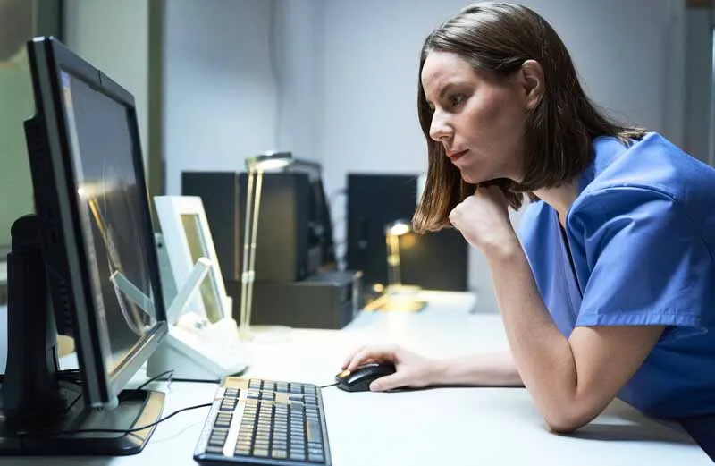 Person in scrubs at computer. Photo: Diego Cervo/Getty Images