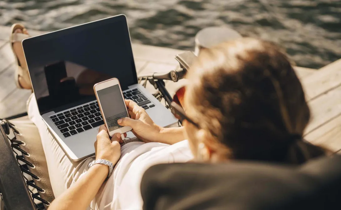 Physician on beach working on laptop and phone