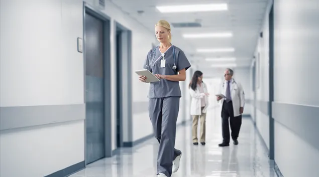 Healthcare professional with tablet in a hospital hallway