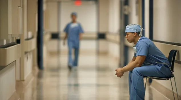 Healthcare worker sits in hospital corridor