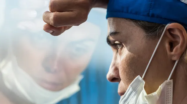 A medical worker leans at a window