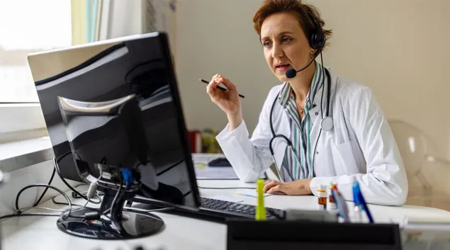 Medical professional at desk with headphones and monitor