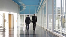 Business people in hospital hallway walking away