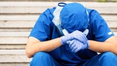 Person in scrubs holding head while seated