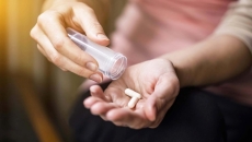 Hands dispensing pills from a bottle