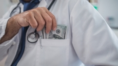 Person tucking dollars into lab coat pocket
