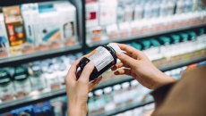 Hands holding a supplement bottle in a pharmacy