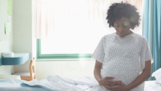 Pregnant person sits on edge of hospital bed
