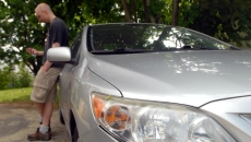 Person looks at phone by car