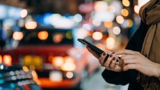 Street scene of person with phone and cars at night