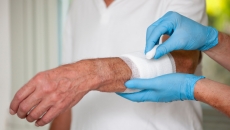 Gloved hands apply wound dressing