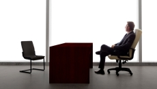 Businessman waiting with empty chair.