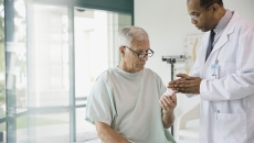 doctor giving male patient prescription bottle at hospital