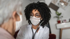 Health professional in mask speaks with a person