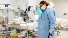 Healthcare worker wiping their forehead in PPE