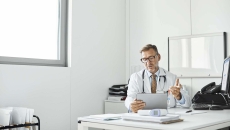 Healthcare professional at desk and holding a tablet