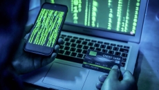 Person on smartphone has credit card out and is also looking at a laptop screen