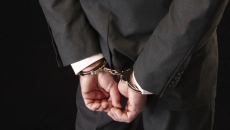 Person in suit handcuffed. Photo: Hirkophoto/Getty Images