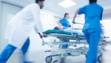 Healthcare providers rushing a hospital bed with a patient in it through a hall