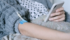 IV in arm of patient holding smartphone