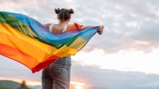 Person holding LGBTQ+ rainbow flag