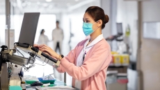 Nurse in hospital standing at laptop