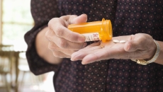 Hands dispensing pills from a bottle