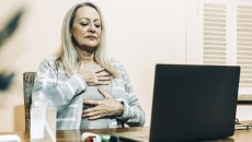 Woman doing breathing exercises in front of a laptop
