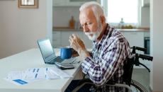 Person looking over medical forms with a calculator and laptop