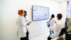 Professionals in a conference room examine a display screen with graphs