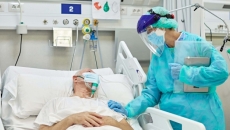 Person wearing PPE at hospital patient's bedside