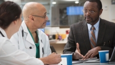 Healthcare professionals sit in meeting with business executive