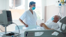 Doctor in mask talking to patient in hospital bed with mask