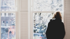 Person staring forlornly out window