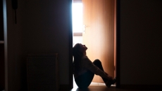 Person sits on floor in doorway