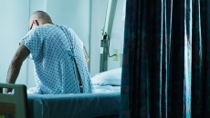 Person sits at side of hospital bed
