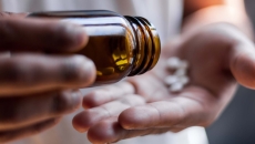 Hands dispense pills from a glass bottle