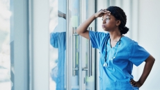 Person in scrubs leans at window
