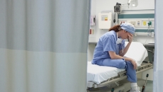 Nurse holding her head in her hand